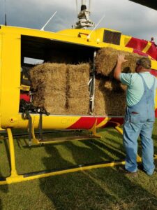 photo of a man loading hay into a helicopter